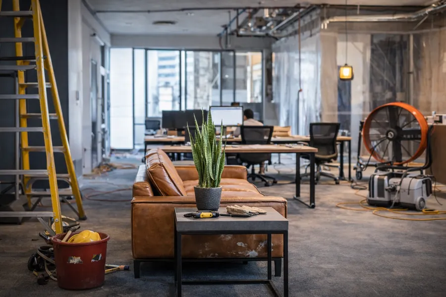 Espace de travail en rénovation avec outils, échelle et mobilier contemporain, illustrant l’univers des travaux et de l’aménagement intérieur.